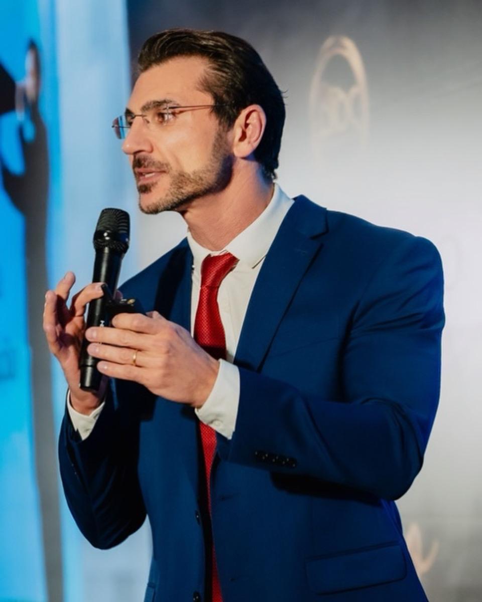 Dr. Alexandre Dell'Aquila palestrando com microfone